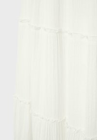 Tissu blanc à étages avec des lignes verticales légèrement texturées et des bords doux froncés sur chaque couche.