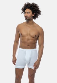 White ribbed boxer briefs with a fitted design, featuring an elastic waistband and a front pouch, against a plain white background.