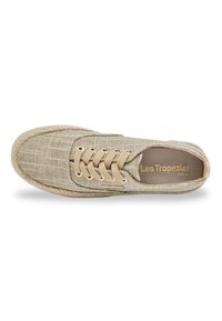 Espadrille en toile beige avec une surface texturée, cinq œillets dorés et des lacets de couleur claire. Présente une semelle en corde et une semelle intérieure marquée.