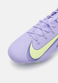 Paarse voetbalschoen gemaakt van gestructureerd synthetisch materiaal, met een gele Nike swoosh, platte veters en een lichtgewicht ontwerp.
