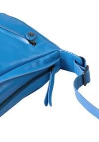 Blaue Ledertasche mit Reißverschluss, die eine glatte Textur, einen Druckknopf-Akzent und einen verstellbaren Trageriemen aufweist.