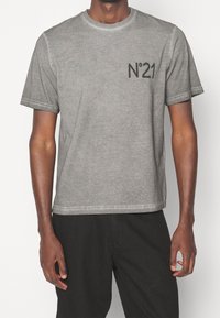 Szary bawełniany T-shirt z krótkimi rękawami, okrągłym dekoltem i nadrukiem "N°21" na lewej piersi. Miękka tekstura i luźny krój.