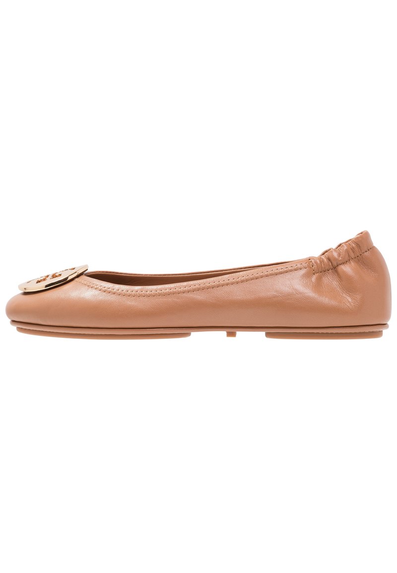 Ballerinas aus tanfarbenem Leder mit runder Zehenpartie, elastischem Einstieg und dekorativem Metalllogo auf dem Blatt. Glatte Textur im gesamten Schuh.