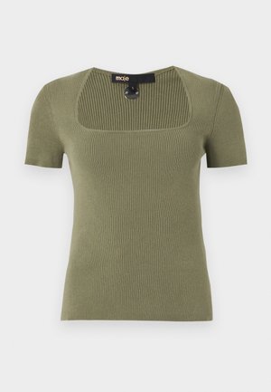 Žena nosí olivovo zelený krátky rebrovaný top, modro-biele pruhované šortky s kvetinovou výšivkou a čierne sandále na podpätku.