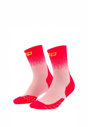 Pair of mid-calf athletic socks in shades of red and pink with yellow text and patterned grip on toes and soles.