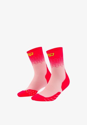 Pair of mid-calf athletic socks in shades of red and pink with yellow text and patterned grip on toes and soles.