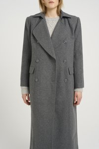 Hallikas villane trench coat, millel on topelt-rinnaga esiosa, laiad klapid ja kaks küljetaskut. All on tekstuuriga kudum.