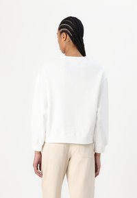 Sweatshirt en coton blanc avec une coupe décontractée, des poignets côtelés et un col rond. Design légèrement cropped avec un minimum de couture dans le dos.