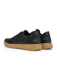 Black leather sneakers featuring a textured finish, round toe, and a contrast gum rubber sole; designed with a low profile and lacing.