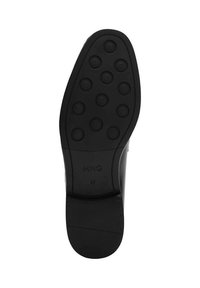 Suela de zapato negra con patrones de agarre circulares, bordes lisos y la marca en relieve "MNG 41" cerca de la parte trasera. Diseño plano con un acabado elegante.