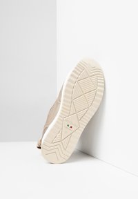 Sneaker beige con una toma liscia e una suola bianca texturizzata. Caratterizzata dal logo del marchio sulla suola e da un motivo sottile per la presa. Taglia 37.