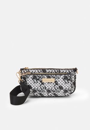 Sac bandoulière à motif noir et blanc avec des accents dorés sur la fermeture éclair, une large bandoulière noire amovible, une poche zippée à l'avant et une plaque avec le logo de la marque.