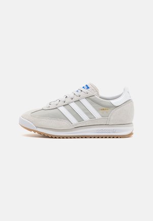 Flacher beigefarbener und weißer Adidas SL 72 Sneaker mit Wildlederpaneelen, drei weißen Streifen, Gummisohle und blauem Logo auf der Zunge, Seitenansicht.