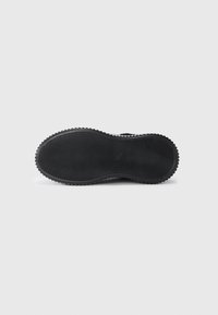 Semelle de chaussure en caoutchouc noir avec des rainures texturées, une forme courbée et une finition lisse. Le bord extérieur présente une légère arête pour une meilleure traction.