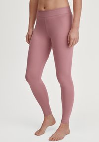 Leggings roses avec une texture lisse, une taille haute et une silhouette ajustée, adaptés pour une utilisation active ou décontractée.