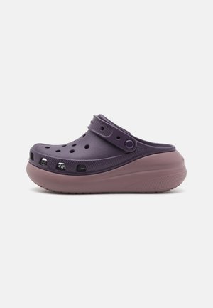 Sabot léger violet avec une épaisse semelle rose texturée, des trous de ventilation et une sangle réglable sur le dessus pour un maintien sécurisé.