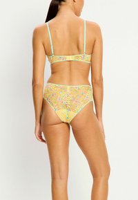 Ensemble de bikini en dentelle avec un motif floral en jaune, rose et bleu. Bretelles réglables et fermeture à crochet au dos.