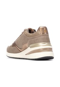 Zapatillas de ante beige con un acento metálico bronce, diseño curvado, paneles texturizados y una gruesa entresuela blanca con una suela exterior de goma negra.