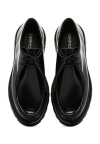 Zapatos de cuero negros con acabado brillante, punta redonda, diseño de cordones y detalles de costura visibles. Suela de goma plana con agarre.