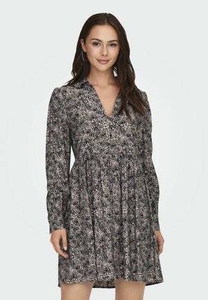 Vestido de manga larga con escote en V, confeccionado en una tela con un patrón moteado en negro y crema, con cintura recogida y falda acampanada.