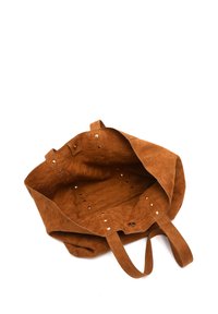 Braune Wildleder-Tote-Tasche mit kurzen Griffen, ungefüttertem Innenraum und dekorativen Metallakzenten. Keine Außenfächer oder Verschlüsse.