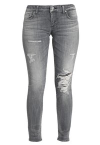 Vaqueros skinnys grises de mezclilla, con un aspecto desgastado y múltiples desgarros y bordes deshilachados. Diseño clásico de cinco bolsillos.