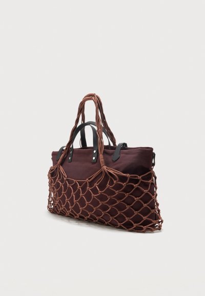 Grand sac fourre-tout en tissu marron avec des poignées noires à l'intérieur d'un sac extérieur en filet de corde marron noué.