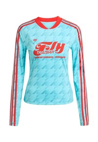 Világoskék, hosszú ujjú sportfelső vörös kiegészítőkkel és három csíkkal. Merész vörös grafikai szöveggel és houndsztooth mintával rendelkezik.
