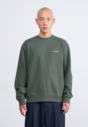 Sudadera verde hecha de tejido suave, con mangas largas, cuello redondo y un pequeño logo blanco en el pecho. Acabado texturizado.