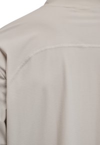 Beige Kurzarmhemd mit strukturiertem Muster, glatten Nähten und dezentem Glanz. Der Stoff wirkt leicht und atmungsaktiv.