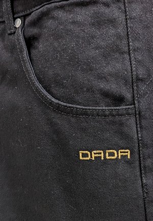 Schwarze Jeans mit einer subtilen Textur, ausgestattet mit einer Fronttasche und dem auf der Seite in Gold gestickten "DADA".