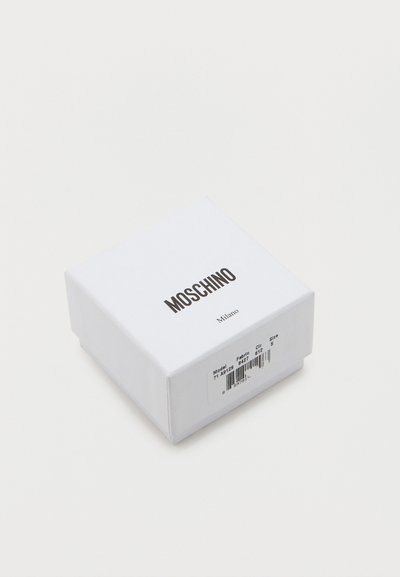 Λευκό κουτί με την επωνυμία Moschino Milano και ετικέτα προϊόντος που εμφανίζει το μοντέλο, το ύφασμα, το χρώμα, το μέγεθος και τη γραμμοκώδικα σε λευκό φόντο.