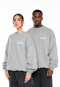 Felpe grigio chiaro con collo a giro e vestibilità leggermente oversized, caratterizzate dal testo "MULTIPLY" in bianco sulla parte anteriore.
