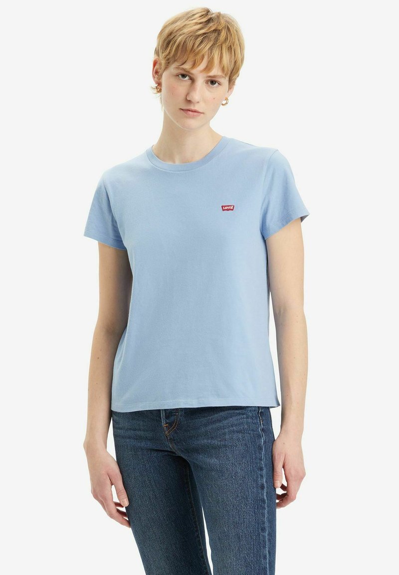 Hellblaues T-Shirt mit kurzen Ärmeln aus Baumwolle, mit einem kleinen roten Logo auf der linken Brust. Gerader Saum und lockere Passform.