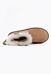 Pantofole in suede marrone con un morbido rivestimento in pelliccia bianca e un anello sul retro per una facile calzata. Presentano una suola piatta e testurizzata per comfort e aderenza.