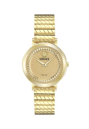 Gold watch with a textured strap and round face. Features include a Greek key pattern and lion emblem, with Swiss made marking on the dial.
