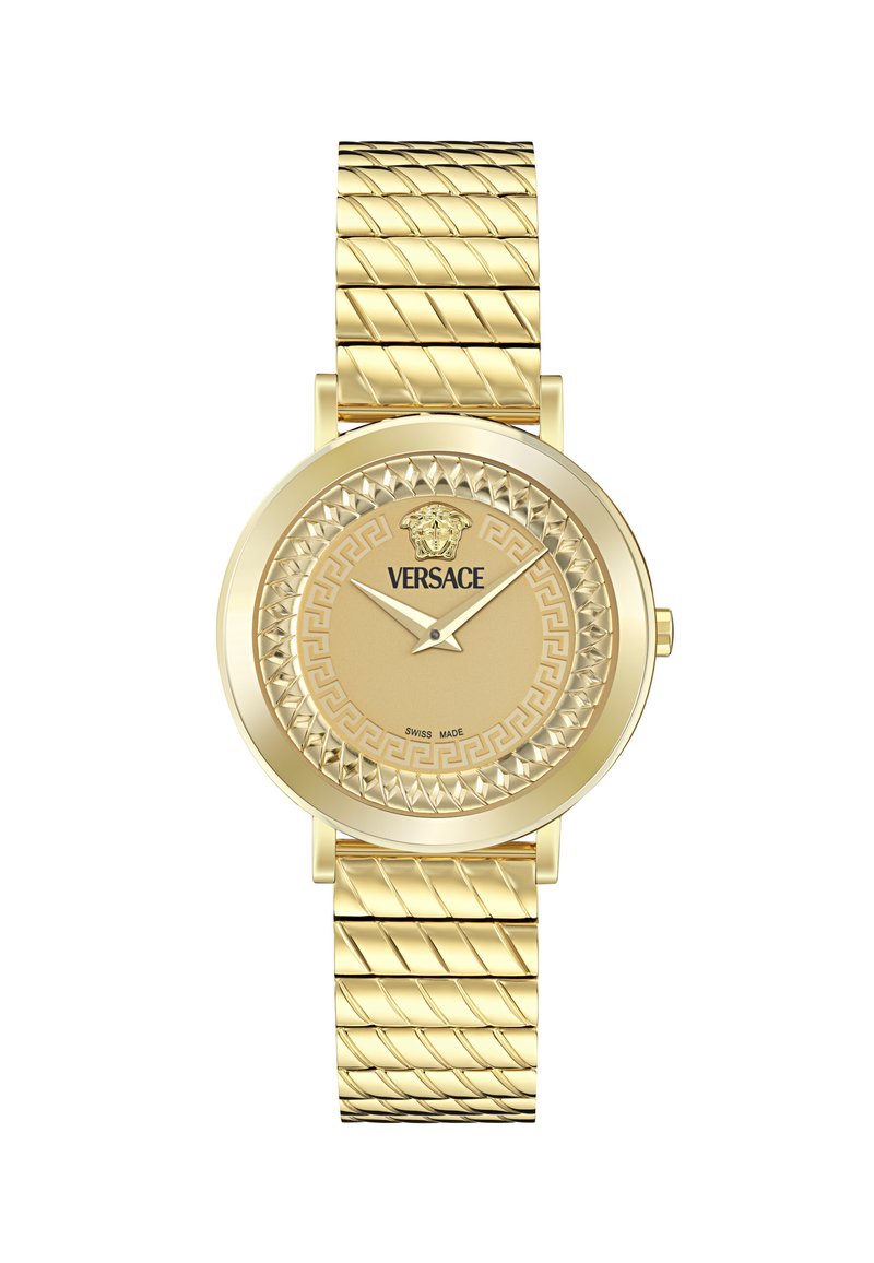 Orologio d'oro con cinturino testurizzato e quadrante rotondo. Le caratteristiche includono un motivo a chiave greca e un emblem di leone, con la dicitura "Swiss made" sul quadrante.