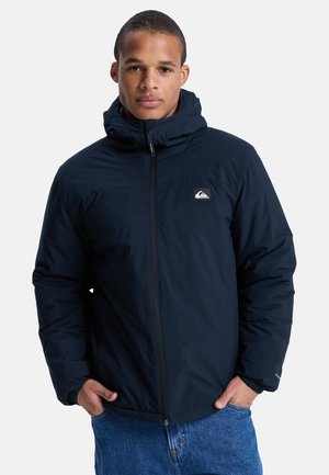 Marineblauwe geïsoleerde jas met een capuchon, voorzien van een ritssluiting, zijzakken en een klein logo-opdruk op de borst. Glad textuur.
