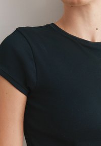Marinblå ribbad t-shirt med kort ärm och rund halsringning, med en slät yta utan synliga mönster eller dekorationer.