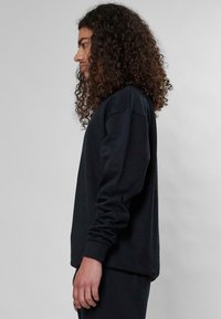 Felpa nera a collo tondo realizzata in cotone, con maniche lunghe, polsini a coste e una vestibilità comoda. Nessun motivo o logo visibile.