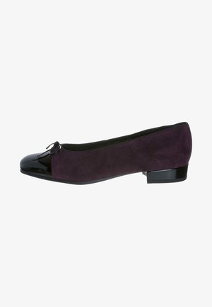 Chausson plat en daim violet avec un embout en vernis noir brillant, détail en nœud à l'avant et un petit talon carré. Texture lisse sur l'ensemble.