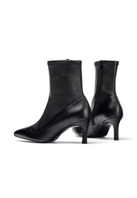 Stivali neri in pelle fino alla caviglia con punte a punta e tacco a stiletto di 7 cm. Presentano una texture liscia e una chiusura con zip sul retro.