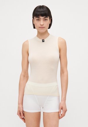 Débardeur crème sans manches avec un col rond, texture côtelée, et une étiquette de marque noire au cou ; associé à un short blanc.