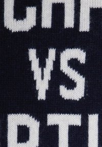 Primo piano di un tessuto a maglia blu navy con le lettere bianche "VS" ben in vista al centro.