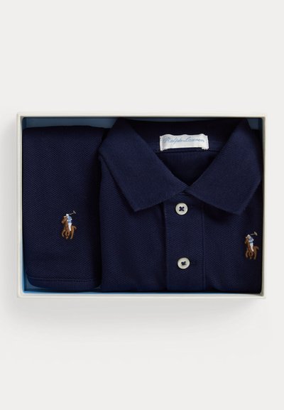 Μπλε σκούρο πόλο Ralph Lauren και αντίστοιχο ύφασμα, διπλωμένα προσεκτικά μέσα σε ένα λευκό ορθογώνιο κουτί δώρου.