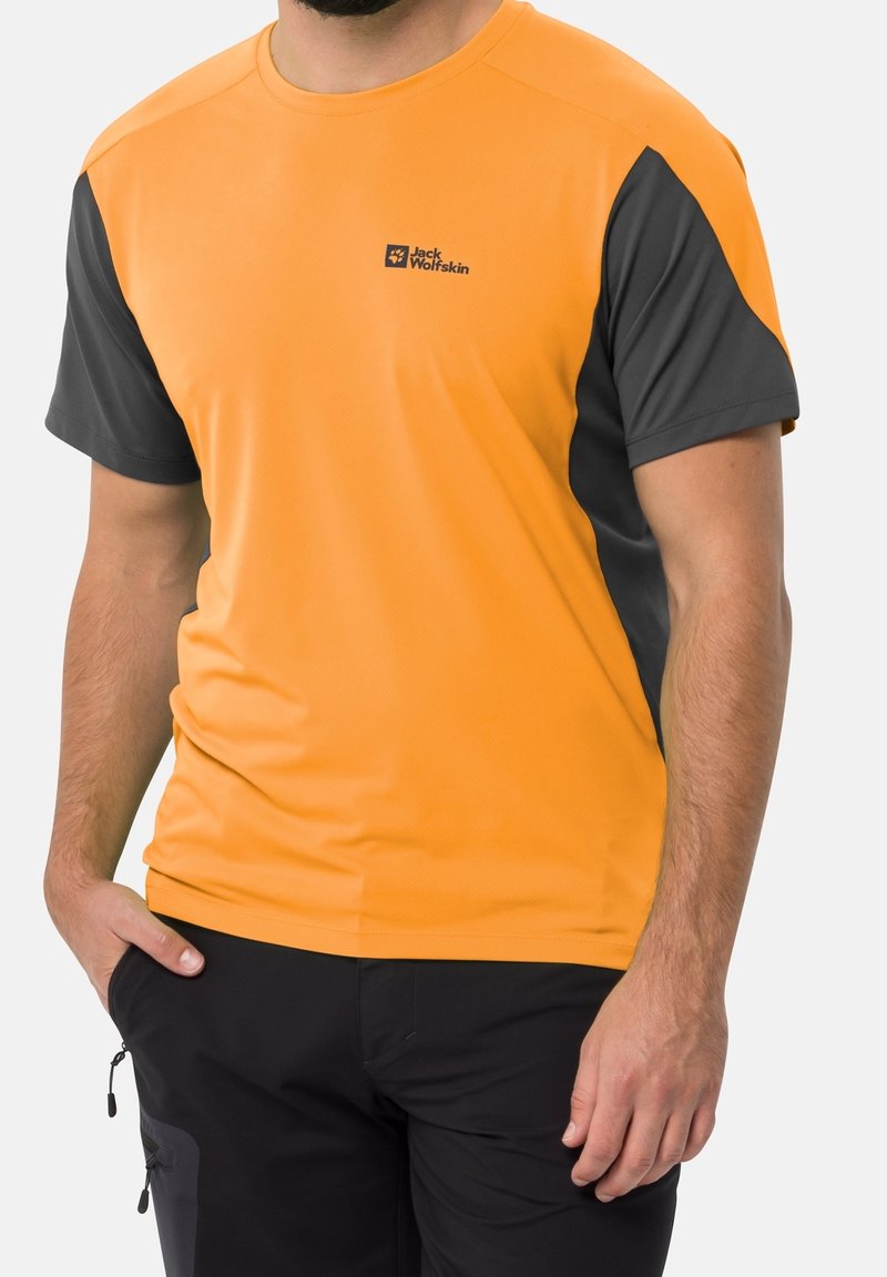 Lyhythihainen urheiluystävällinen paita oranssina harmailla yksityiskohdilla. Valmistettu kosteutta siirtävästä kankaasta, jossa on Jack Wolfskin -logo rinnassa.