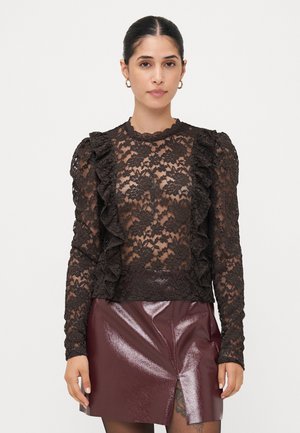 Black lace top with long sleeves and ruffled detailing, paired with a burgundy shiny faux leather skirt featuring a front slit.