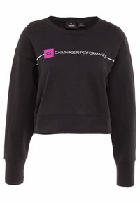 Zwarte cropped sweatshirt met lange mouwen, ronde hals en "Calvin Klein Performance" logo-tekst over de borst met een paarse vierkante detail.