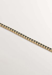 Pulsera de oro hecha de segmentos de metal enlazados, que muestra piedras negras alternas engastadas en garras, con un acabado suave y forma rectangular.