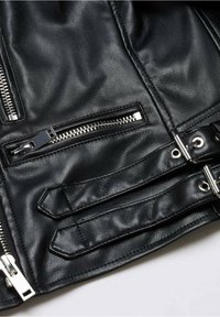 Czarna skórzana kurtka z zamykanymi na zamek kieszeniami i metalowymi dodatkami. Faktura jest gładka, z widocznym przeszyciem i detalami.